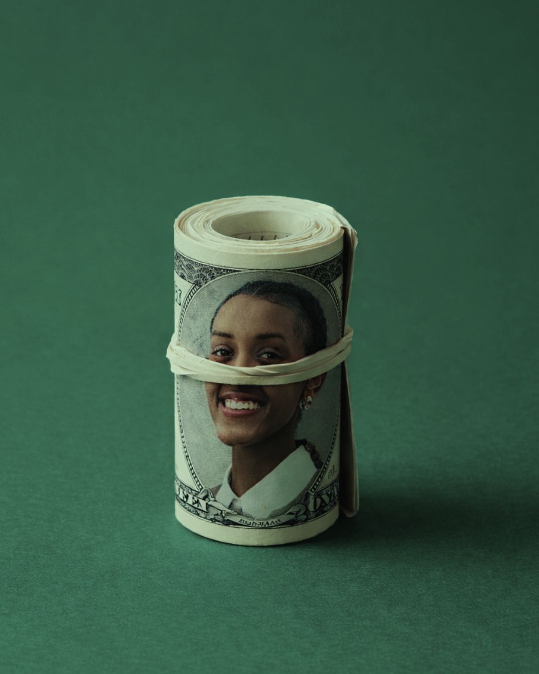 Rolled dollar bill bearing a portrait, on a green background